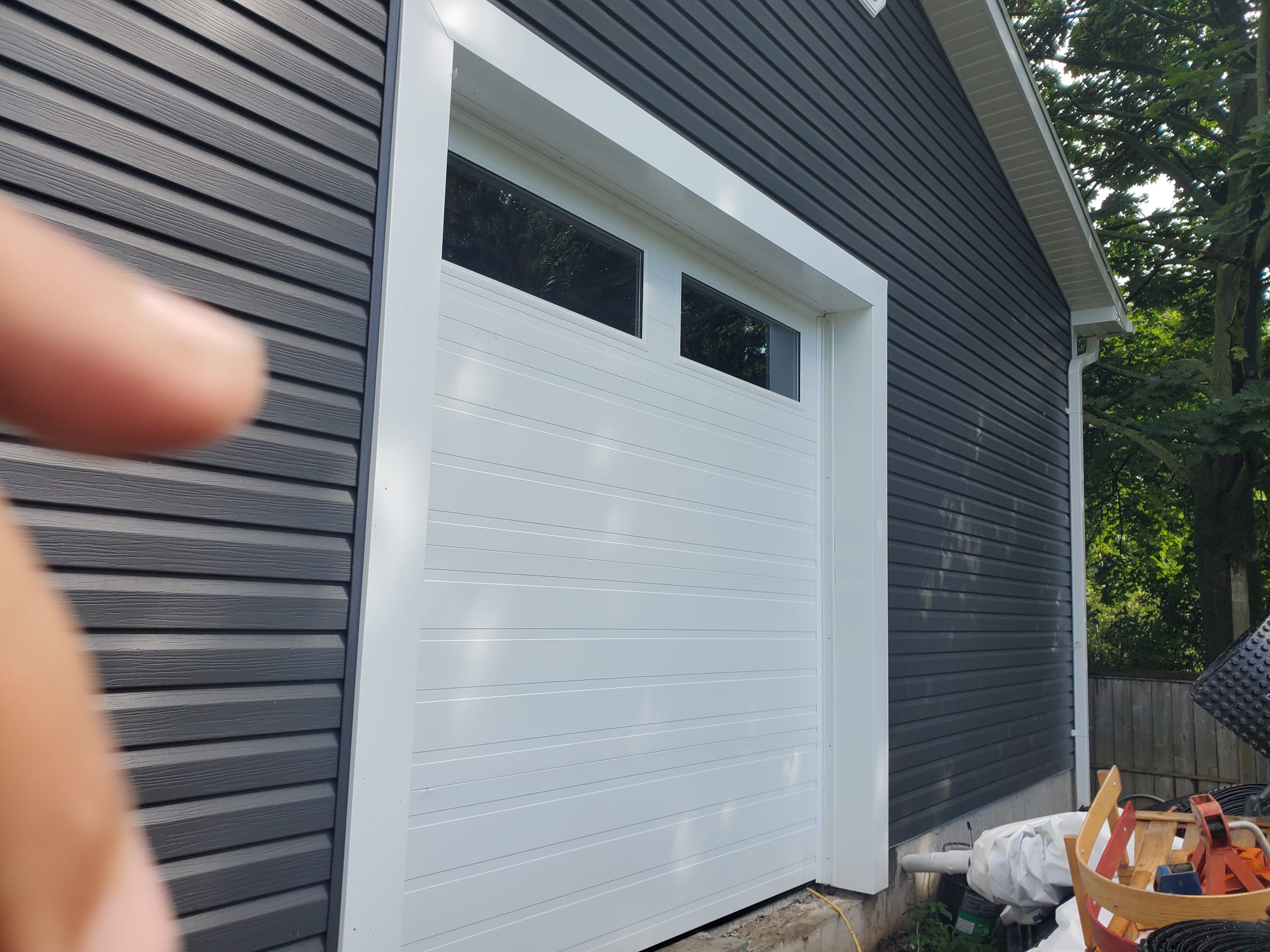 Completed white modern garage door on a dark-sided garage